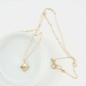 Delicate gold chain necklace with gold native motif cross pendant with inset diamond.