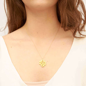 Woman wearing a gold chain necklace with cast gold tree canopy inspired pendant.