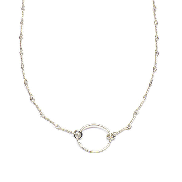Close-up of delicate silver chain necklace with a simple circle pendant.