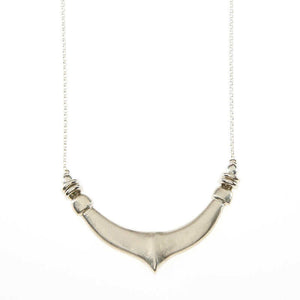 Close-up of delicate silver chain necklace with chunky hand cast organic curved pendant.