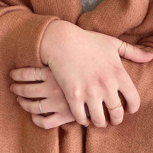 Detail of woman's hand wearing gold ring with two loops of wire.