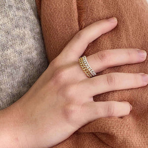 Close-up of hand wearing a gold and a silver wide chain ring.